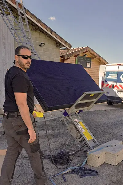 Rémy Desjardins, gérant de la société Elec'eaux en train de commander la montée de panneaux solaires sur une toiture avec une échelle monte-charge